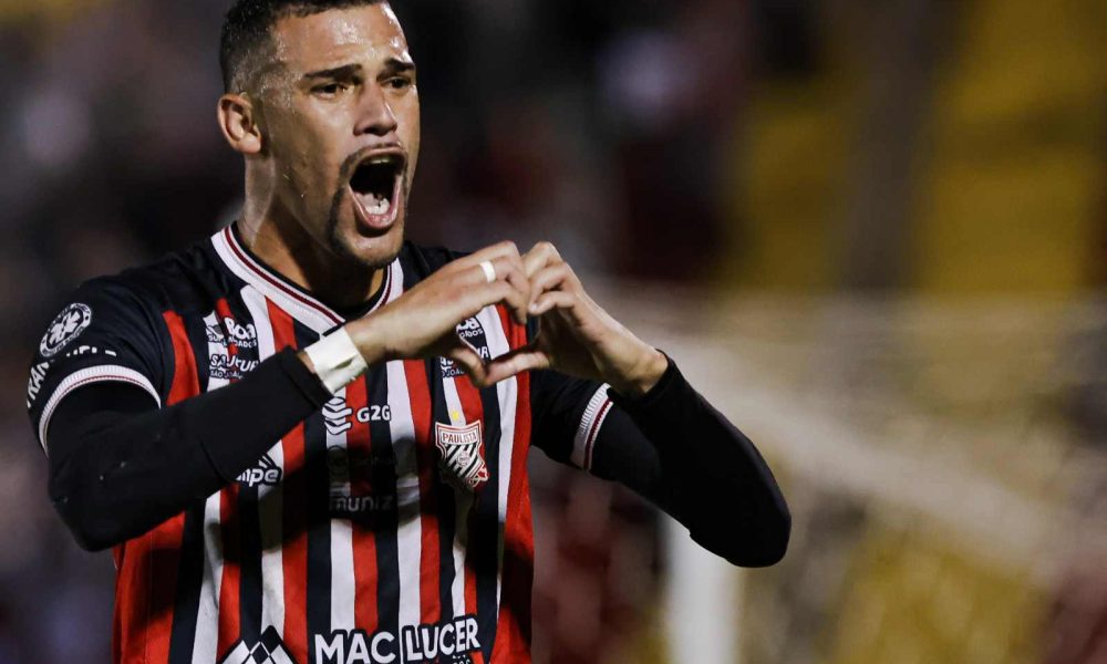 Jogador do Paulista comemorando gol com gesto de coração na semifinal da Bezinha 2024, vestindo o uniforme tricolor do clube.