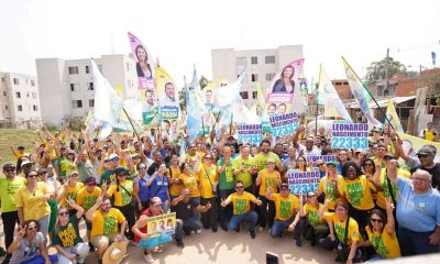 Grupo de apoiadores de Parimoschi em caminhada de campanha no Jardim Novo Horizonte, segurando bandeiras e cartazes de candidatos aliados.