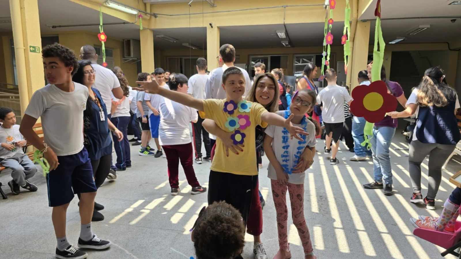 APAE Jundiaí realiza baile da primavera para alunos; jovens se divertem com professores em meio às flores.