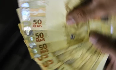 Imagem de várias notas de 50 reais sendo manuseadas rapidamente, representando do dinheiro esquecido em bancos no Brasil.