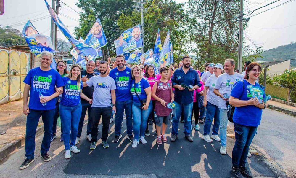 Gustavo Martinelli e grupo de apoiadores em passeata na região sul de Jundiaí, segurando bandeiras de campanha e interagindo com moradores.