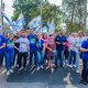 Gustavo Martinelli e grupo de apoiadores em passeata na região sul de Jundiaí, segurando bandeiras de campanha e interagindo com moradores.