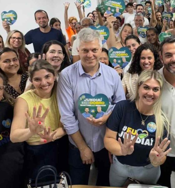 Grupo de educadores e Gustavo Martinelli em reunião de campanha, segurando placas com o slogan "Jundiaí merece o dobro", mostrando apoio