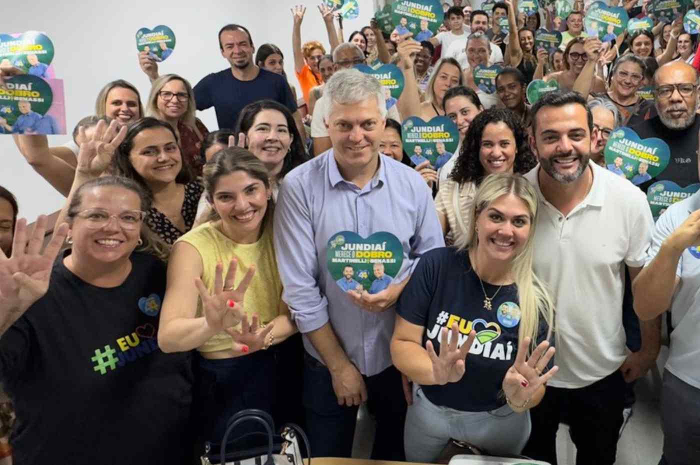 Grupo de educadores e Gustavo Martinelli em reunião de campanha, segurando placas com o slogan "Jundiaí merece o dobro", mostrando apoio