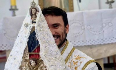 Padre Fabrício Rodrigues segurando santa no altar de igreja.