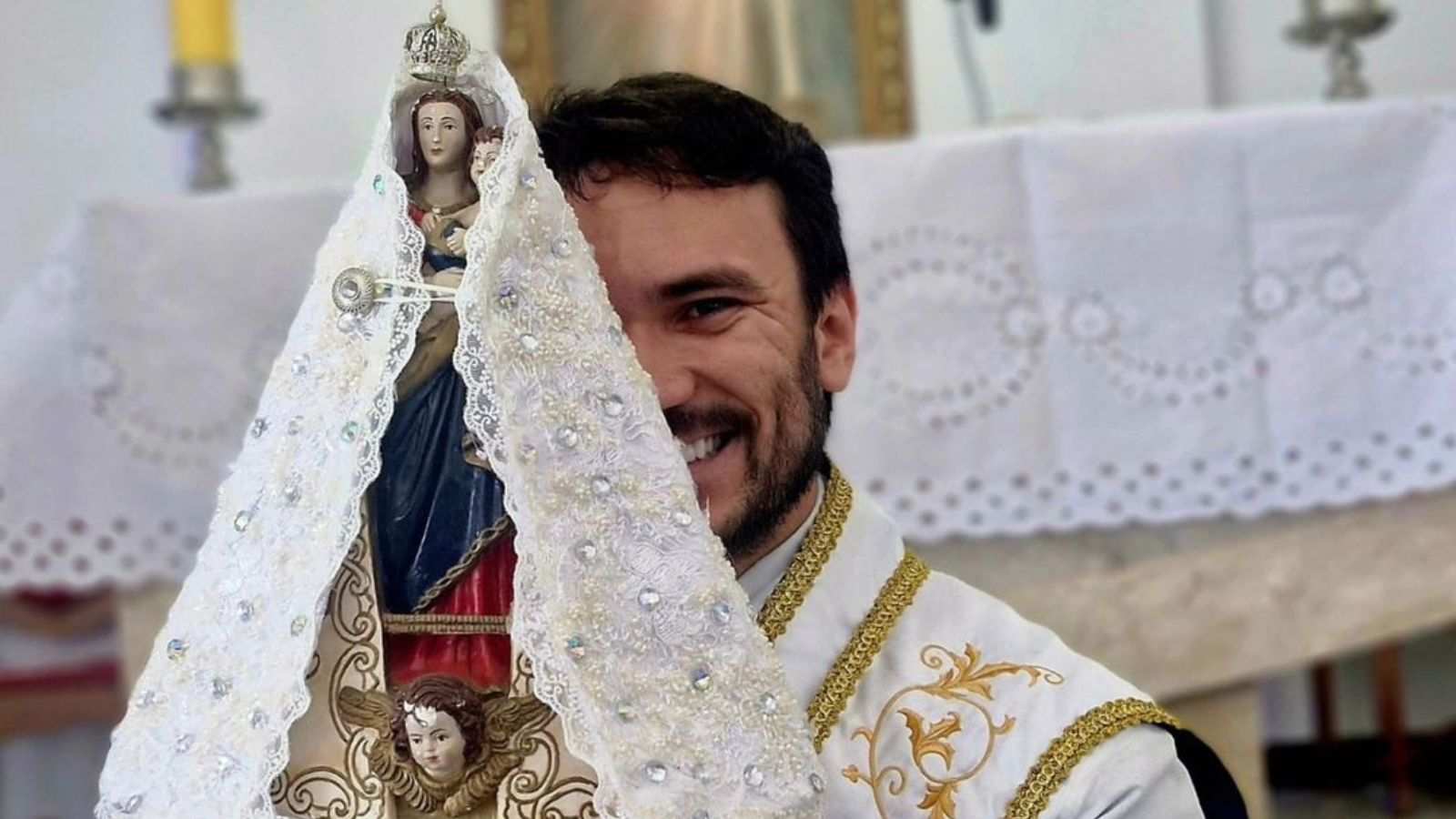 Padre Fabrício Rodrigues segurando santa no altar de igreja.