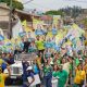 Multidão em caminhada política com cartazes de José Antônio Parimoschi e diversos candidatos pelas ruas de Jundiaí durante campanha eleitoral.