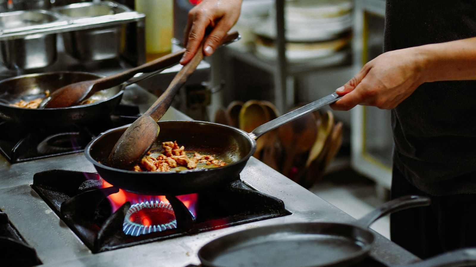 Vagas de emprego para trabalhar em cozinhas estão abertas e, na imagem, mostra uma pessoa cozinhando, ilustrando atividade do cargo.