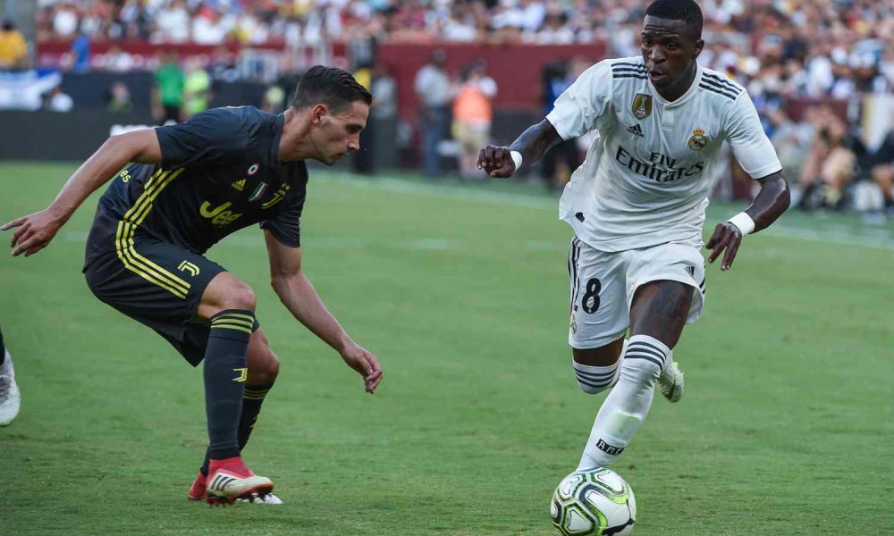 Vini Jr. do Real Madrid dribla defensor da Juventus em partida de pré-temporada, usando agilidade para avançar com a bola.