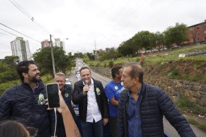 Parimoschi lidera carreata com apoiadores em Jundiaí, acompanhado de vereadores e prefeito, com fila de veículos ao fundo.