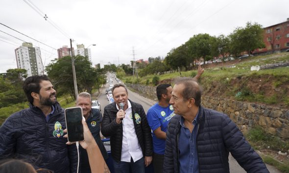 Parimoschi lidera carreata com apoiadores em Jundiaí, acompanhado de vereadores e prefeito, com fila de veículos ao fundo.