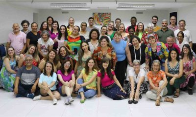 Grupo de coralistas do Colégio Divino Salvador reunidos em uma sala de ensaio, sorrindo e posando para foto em comemoração.