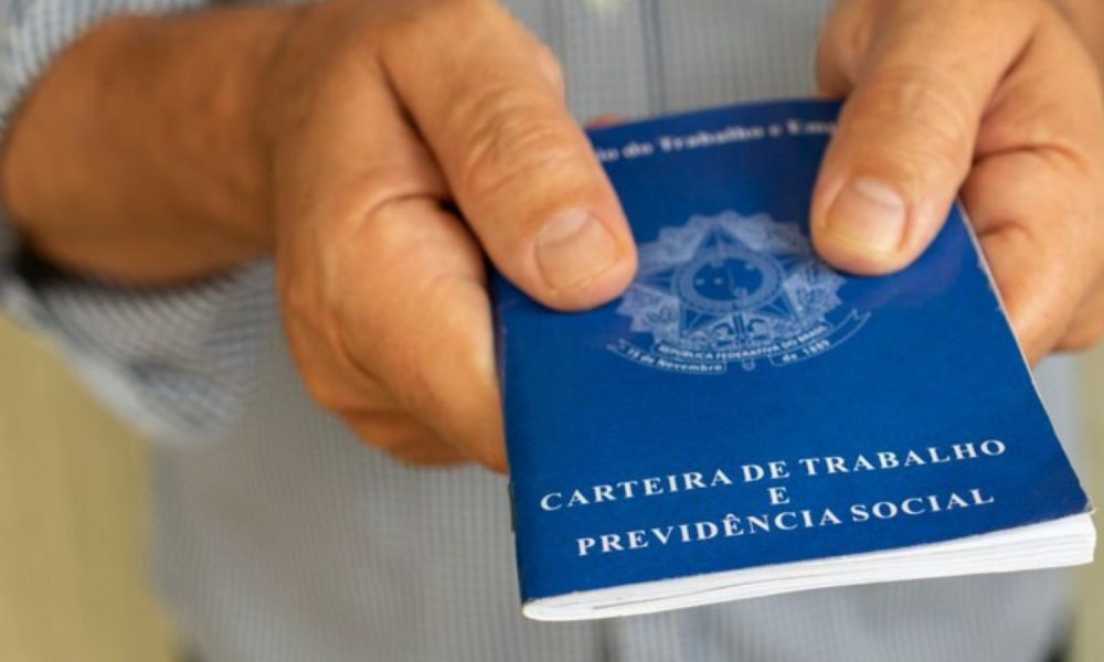 Vagas temporárias exigem carteira de trabalho; foto de mãos masculinas segurando o documento.