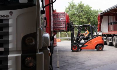 Rapaz com empilhadeira colocando mercadoria em caminhão no galpão da Coca-Cola FEMSA.