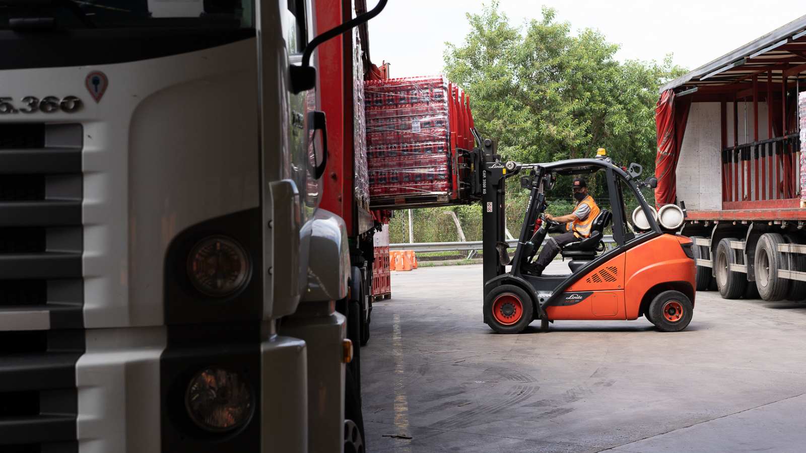 Rapaz com empilhadeira colocando mercadoria em caminhão no galpão da Coca-Cola FEMSA.