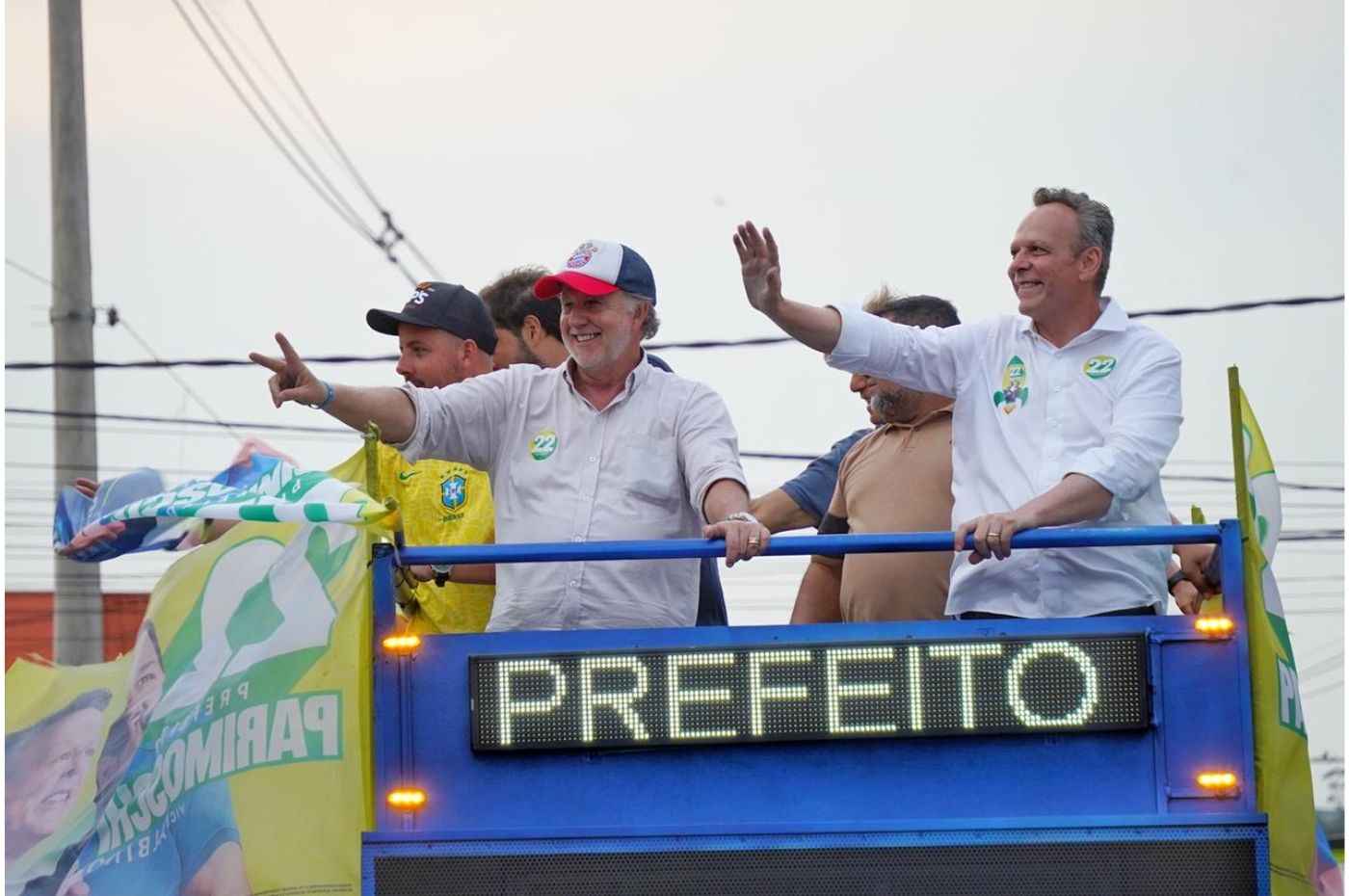 José Antônio Parimoschi e apoiadores acenam em carreata da vitória em Jundiaí, destacando campanha para prefeito, com bandeiras e placas.