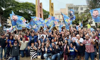 Grupo de apoiadores com bandeiras de Gustavo Martinelli em caminhada no centro de Jundiaí, levantando mãos com o número 44