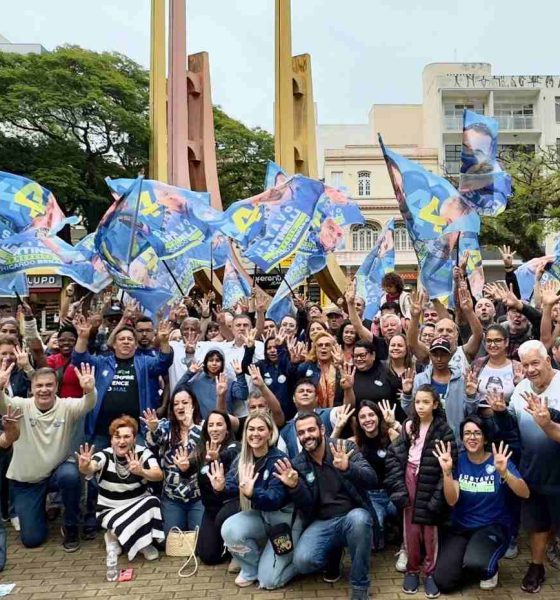 Grupo de apoiadores com bandeiras de Gustavo Martinelli em caminhada no centro de Jundiaí, levantando mãos com o número 44