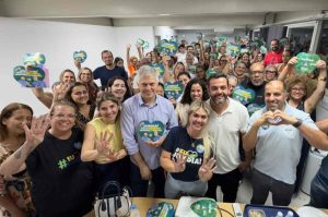 Grupo de pessoas sorrindo, segurando cartazes de campanha 'Jundiaí merece o dobro' com Gustavo Martinelli e outros candidatos em evento político.