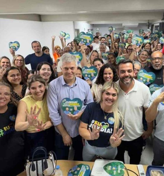 Grupo de pessoas sorrindo, segurando cartazes de campanha 'Jundiaí merece o dobro' com Gustavo Martinelli e outros candidatos em evento político.