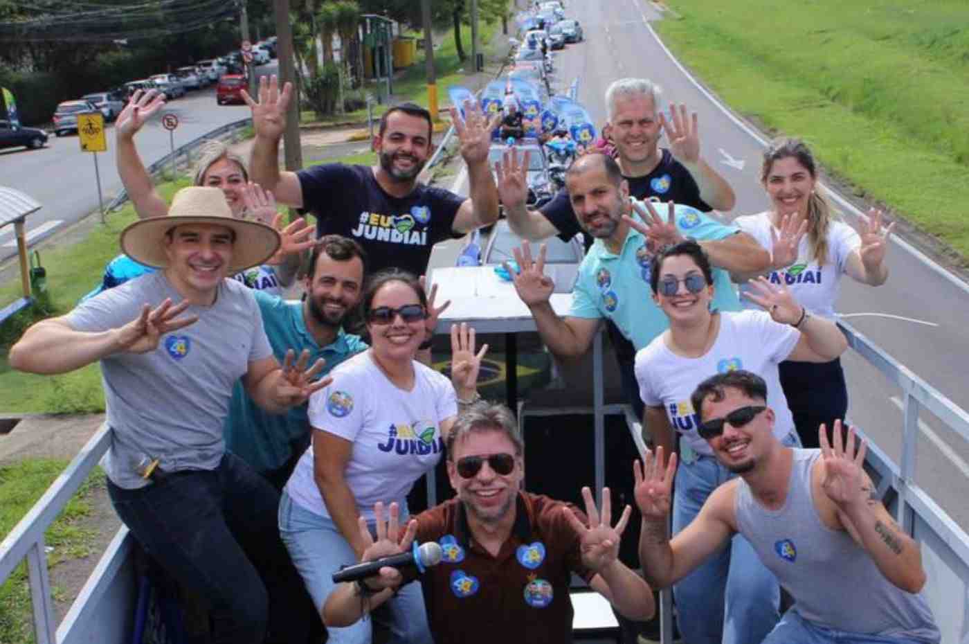 Gustavo Martinelli e Ricardo Benassi, acompanhados de apoiadores, posam em carreata em Jundiaí, fazendo o número "4" com as mãos.