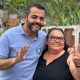 Gustavo Martinelli em caminhada no bairro Ivoturucaia, sorrindo e fazendo gesto de quatro com uma moradora local.