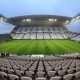 Estádio Neo Química Arena vazio com cadeiras brancas, gramado bem cuidado e iluminação ligada antes de uma partida de futebol.