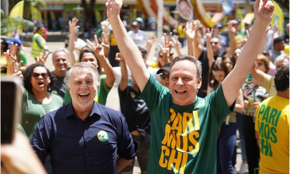 Candidato José Antonio Parimoschi e apoiadores comemoram em caminhada da vitória em Jundiaí, ao lado de líder político usando camisa verde.