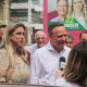 José Antonio Parimoschi e Quézia de Lucca durante campanha em Jundiaí, conversando com a imprensa em frente a um cartaz eleitoral