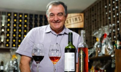 Proprietário da vinícola Martins com os vinhos premiados em frente à mesa.