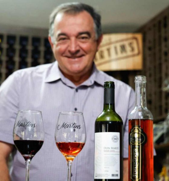 Proprietário da vinícola Martins com os vinhos premiados em frente à mesa.