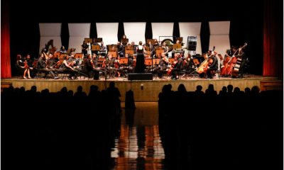 Orquestra Sinfônica Municipal de Jundiaí no Polytheama durante apresentação no palco com músicos tocando instrumentos clássicos, regente ao centro e público assistindo.