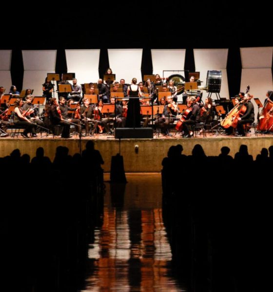 Orquestra Sinfônica Municipal de Jundiaí no Polytheama durante apresentação no palco com músicos tocando instrumentos clássicos, regente ao centro e público assistindo.